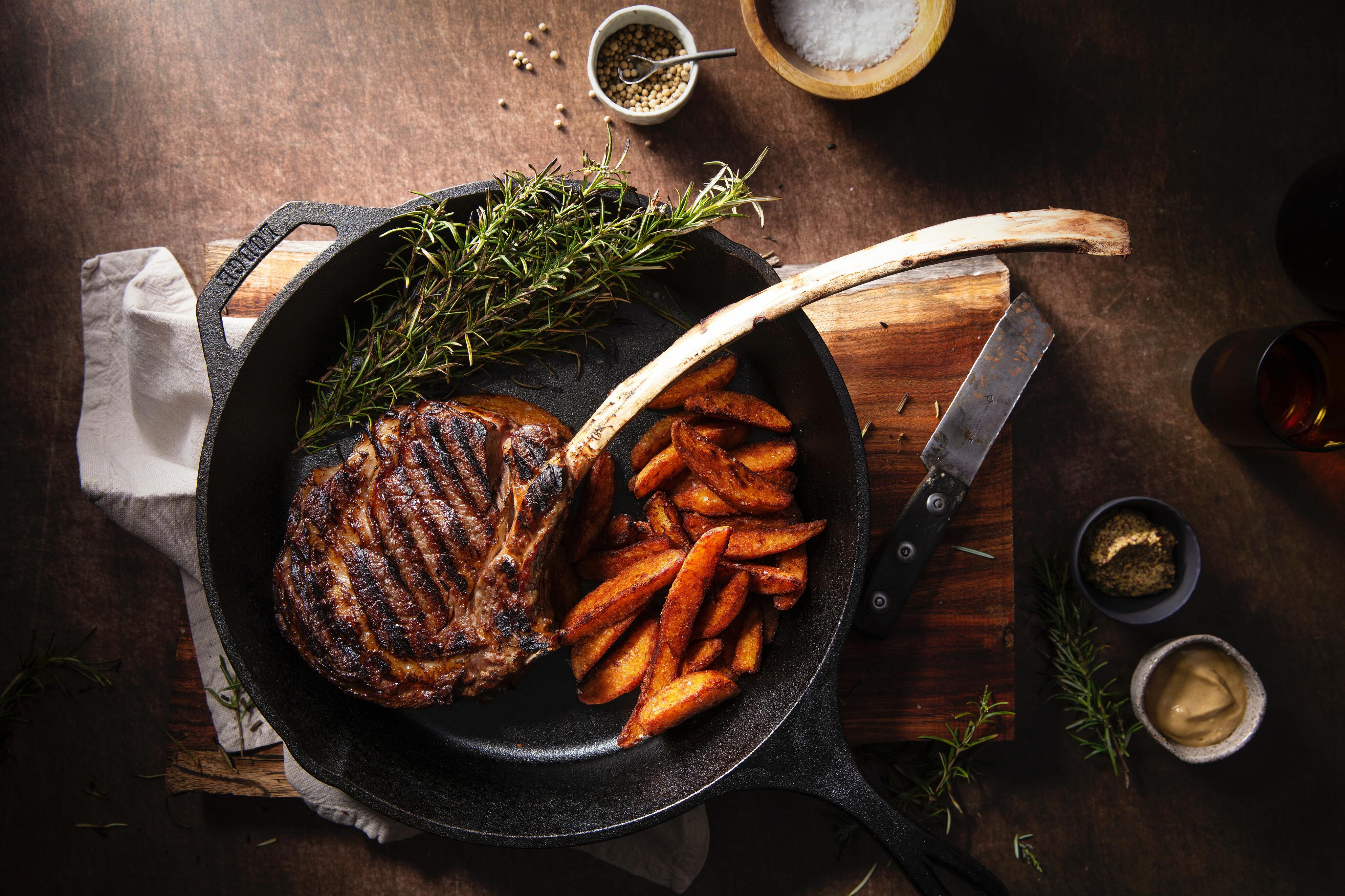 iron-skillet-with-meat-and-potatoes-on-wooden-board.jpg